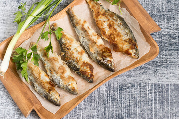 
Roasted fish. Roasted river fish roach on an old brown wooden tray.