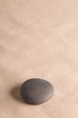 Fototapeta na wymiar round dark stone on sand, minimal zen yoga or spa wellness background with copy space