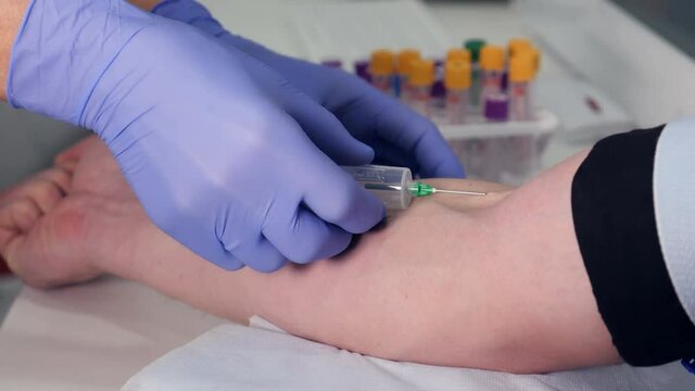 Doctor is taking a blood sample from a vein at a clinic. Close-up.