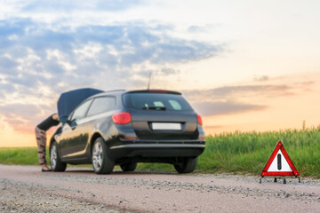 Frau schaut sich kaputtes Auto genau an
