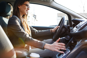 Attractive  businesswoman driving a car secured with seat belt.
