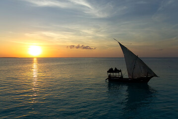Fototapeta premium Stunning sunset captured north on Zanzibar, Tanzania, Africa. Sailboat passing by.