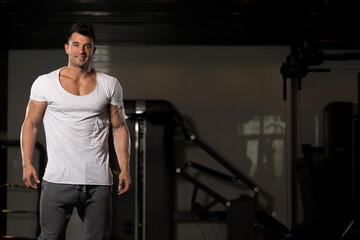 Fototapeta na wymiar Strong Man in White T-shirt Background Gym