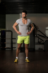 Fototapeta na wymiar Strong Man in Grey T-shirt Background Gym
