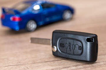 car key and  blue car toy on wooden desk.
