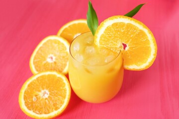 Fresh orange juice on pink background  