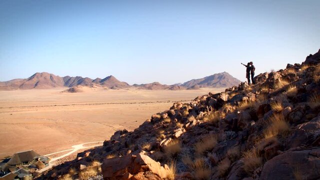 Tourists standing on the edge of a mountain looking in the desert