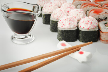 Sushi with soy and sticks on white
