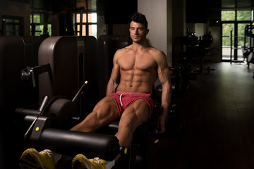Fototapeta na wymiar Training Legs On Machine In Gym