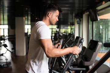 Fototapeta na wymiar Healthy Man Doing Aerobics Elliptical Walker In Gym