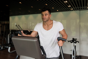 Fototapeta na wymiar Healthy Athlete Doing Aerobics Elliptical Walker In Gym