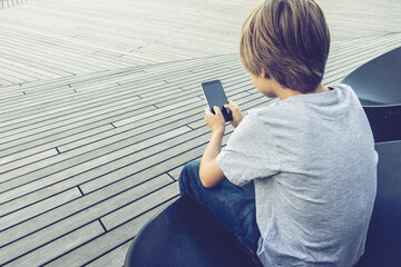 Boy with mobile phone. Back view.