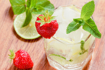 A glass of cold water with lemon and lime, ice cubes and mint leaves