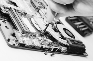 Repair laptops, close-up of hands and dismantled old computer. Вlack and white photography.