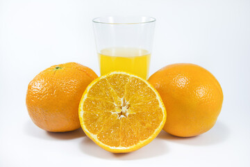 Perfectly retouched sliced orange in the middle. Fresh oranges isolated on white background. Freshly picked oranges. Orange juice. Glass of orange juice. Close up.