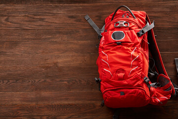 Top view of the bright orange travel backpack on a wooden background.