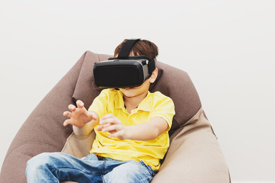Boy plays game with virtual reality glasses indoors