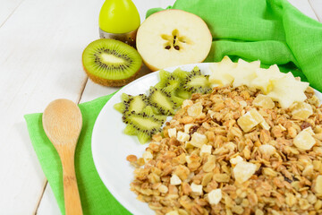 Breakfast with granola, fresh kiwi and apple on green tissue