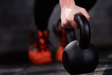 Close-up photo of young athlete woman's hand while doing push ups on kettlebells against brick wall in the gym.