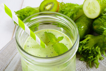 Healthy green smoothie in jar with cucumber, kiwi, salad and spices