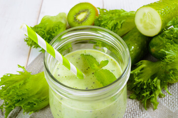 Healthy green smoothie in jar with cucumber, kiwi, salad and spices
