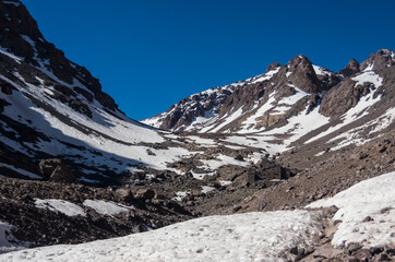Obraz premium Toubkal national park in springtime with mount, cover by snow and ice, Refuge Toubkal, start point for hike to Jebel Toubkal, – highest peak of Atlas mountains and Morocco