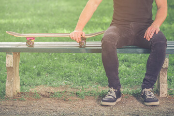 Skateboarder sitting on bench in the park