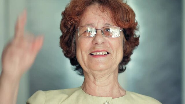 Senior woman putting on her glasses and happily surprised looking at camera