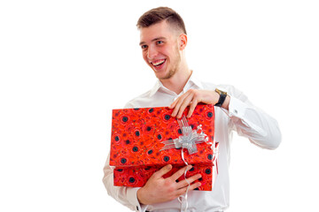 handsome gay guy in a white shirt holding a great gift and laughs is isolated on a white background