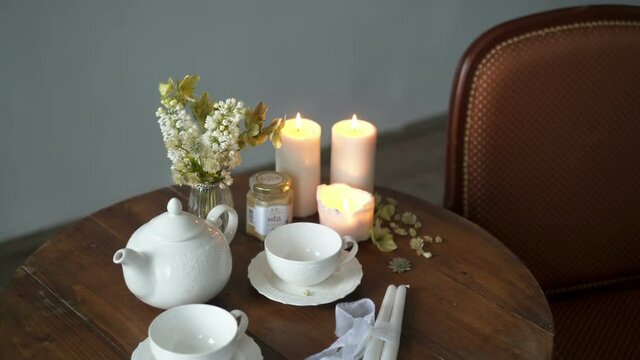 Teapot and cups on a table with flowers and candles