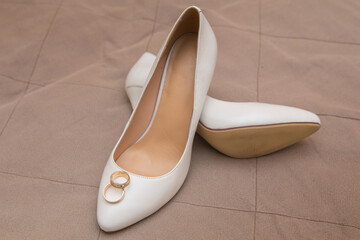 gold wedding rings lie on white shoes