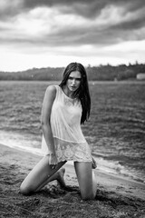 Wet gorgeous model posing on the beach in the rain (black and white)