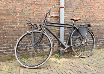 Naklejka premium Sturdy black retro style bicycle parked against an ancient brick wall, Amsterdam, The Netherlands