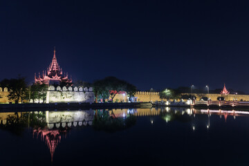 Lit citadel's wall, bastion and pyatthat (spire) and moat at the royal Mandalay Palace in Mandalay, Myanmar (Burma) at night. Copy space.