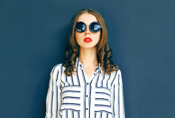 Fashion portrait elegant woman in a black sunglasses posing over a gray background