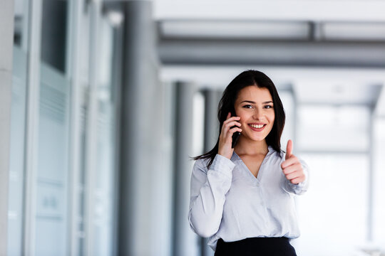 Attractive woman talking on phone and showing thums up