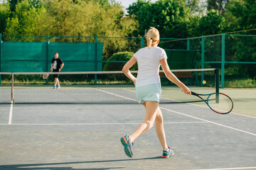 Fototapeta premium Tennis player playing on the court on a sunny day. Young sport woman training outdoors. Healthy lifestyle concept.
