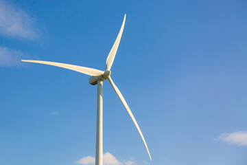 Wind turbine close up against blue sky with clouds