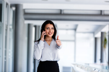 Attractive woman talking on phone and showing thums up