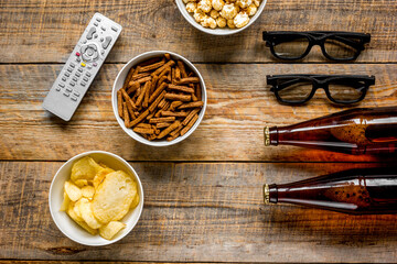 film whatching party with beer, crumbs, chips and pop corn wooden background top view mockup