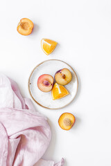 tropical fruits design with orange and peach on fabric white table background top view