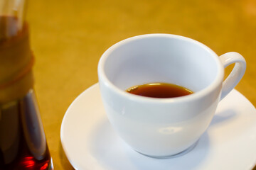 Cup of coffee on white plate and wood table background