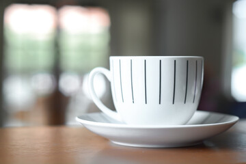 Cup of coffee on a wooden desk and living room background