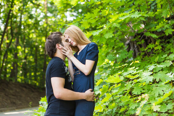 Fototapeta premium Young couple outdoor portrait. Beautiful pretty girl kissing handsome boy. Sensual photo