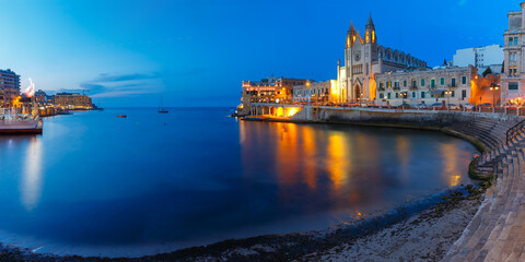 Naklejka premium Balluta Bay and Neo-Gothic Church of Our Lady of Mount Carmel, Balluta parish church, during evening blue hour, Saint Julien, Malta