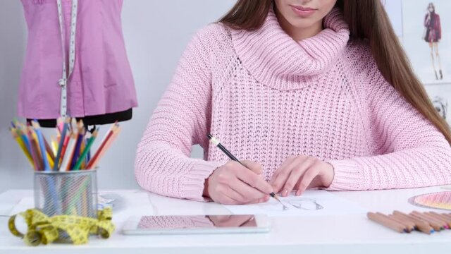 Fashion designer in his workshop draws sketches for the magazine