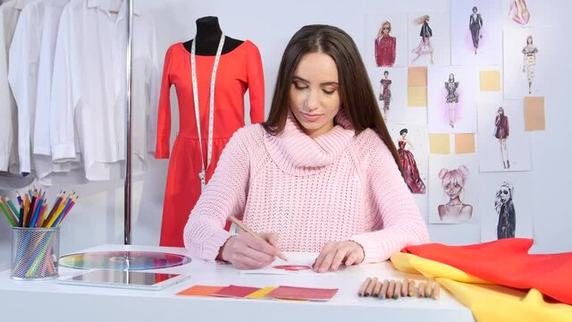 Girl designer draws a sketch of red dress for a youth fashion magazine