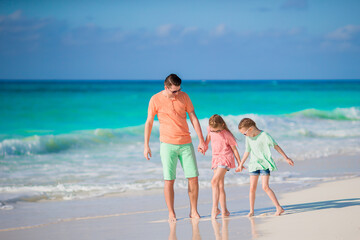 Family of dad and kids on white tropical beach have a lot of fun
