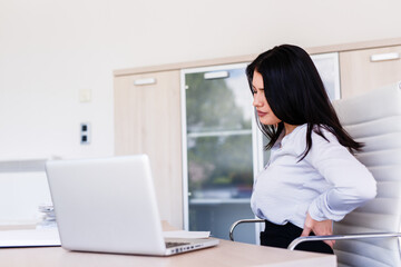 Businesswoman having back pain after long sitting in her office