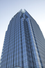 Obraz premium Downtown office building with many floors and blue sky reflected in windows
